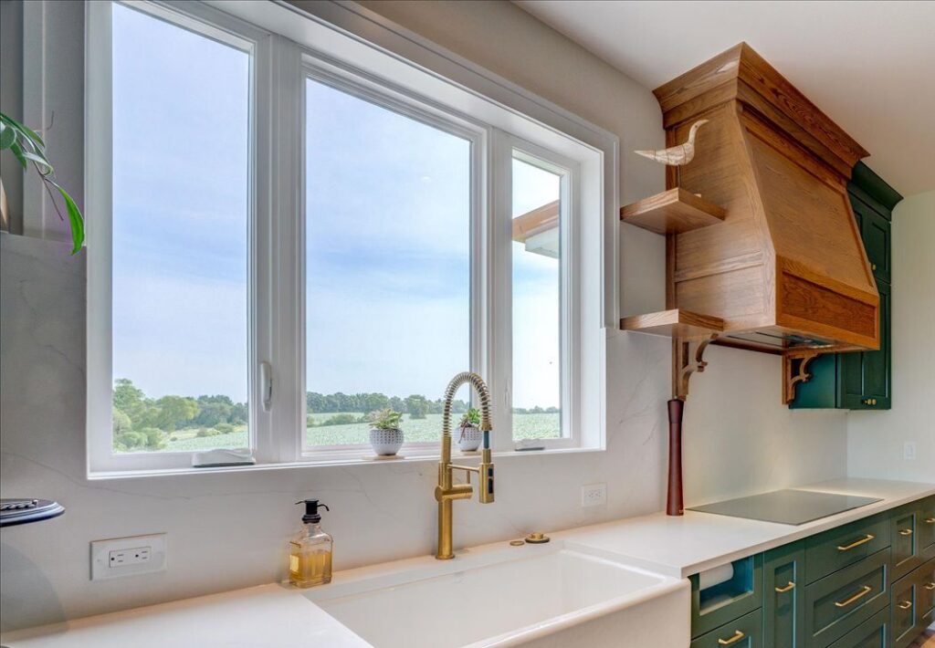 Kitchen picture window above a farmhouse sink with a gold faucet