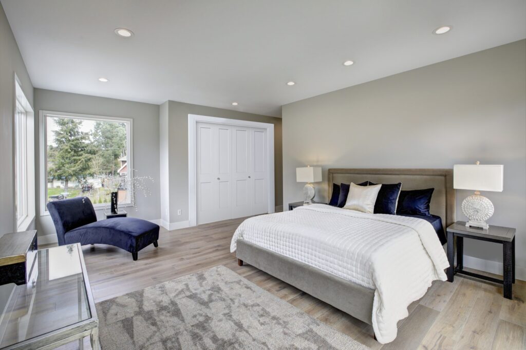 Bedroom with white bifold closet doors beside a window