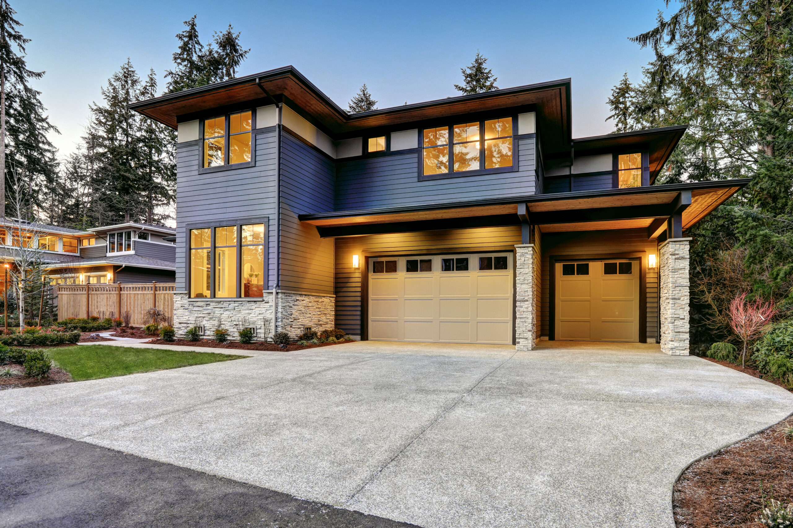 Two-storey home with blue-grey siding and a two-car garage at dusk