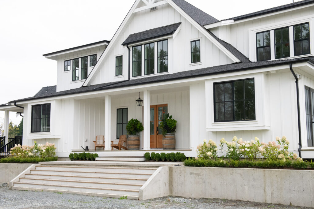 White farmhouse with black-framed windows and a wood front door