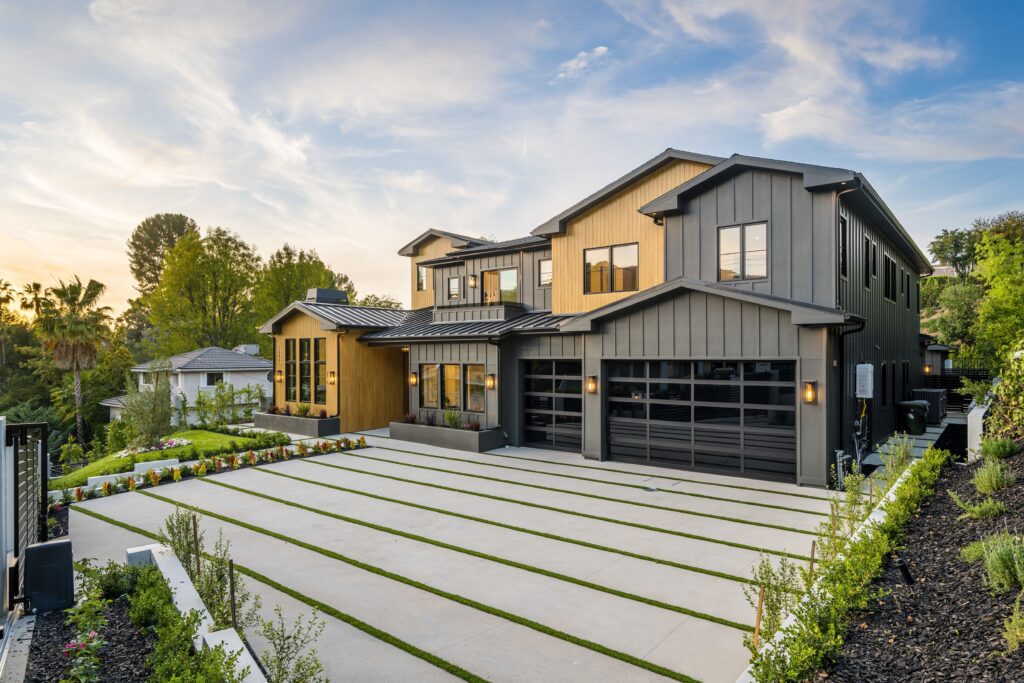 Modern two-storey home with grey and wood siding and black garage doors