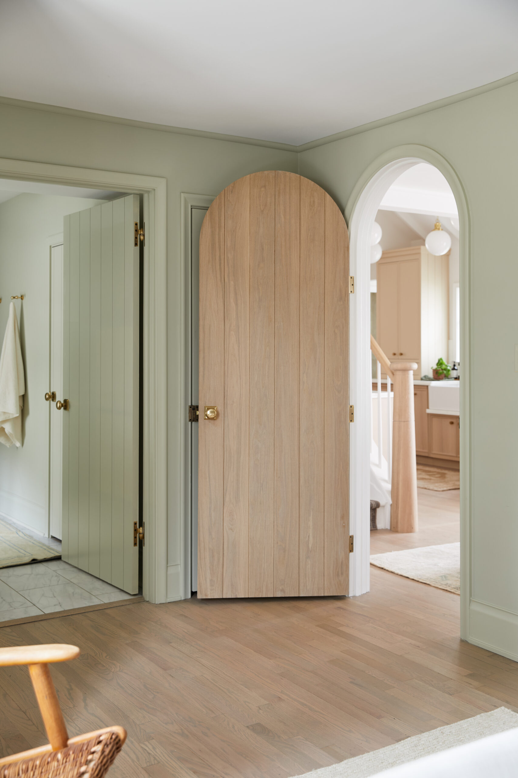 Arched white oak interior door in a sage green room
