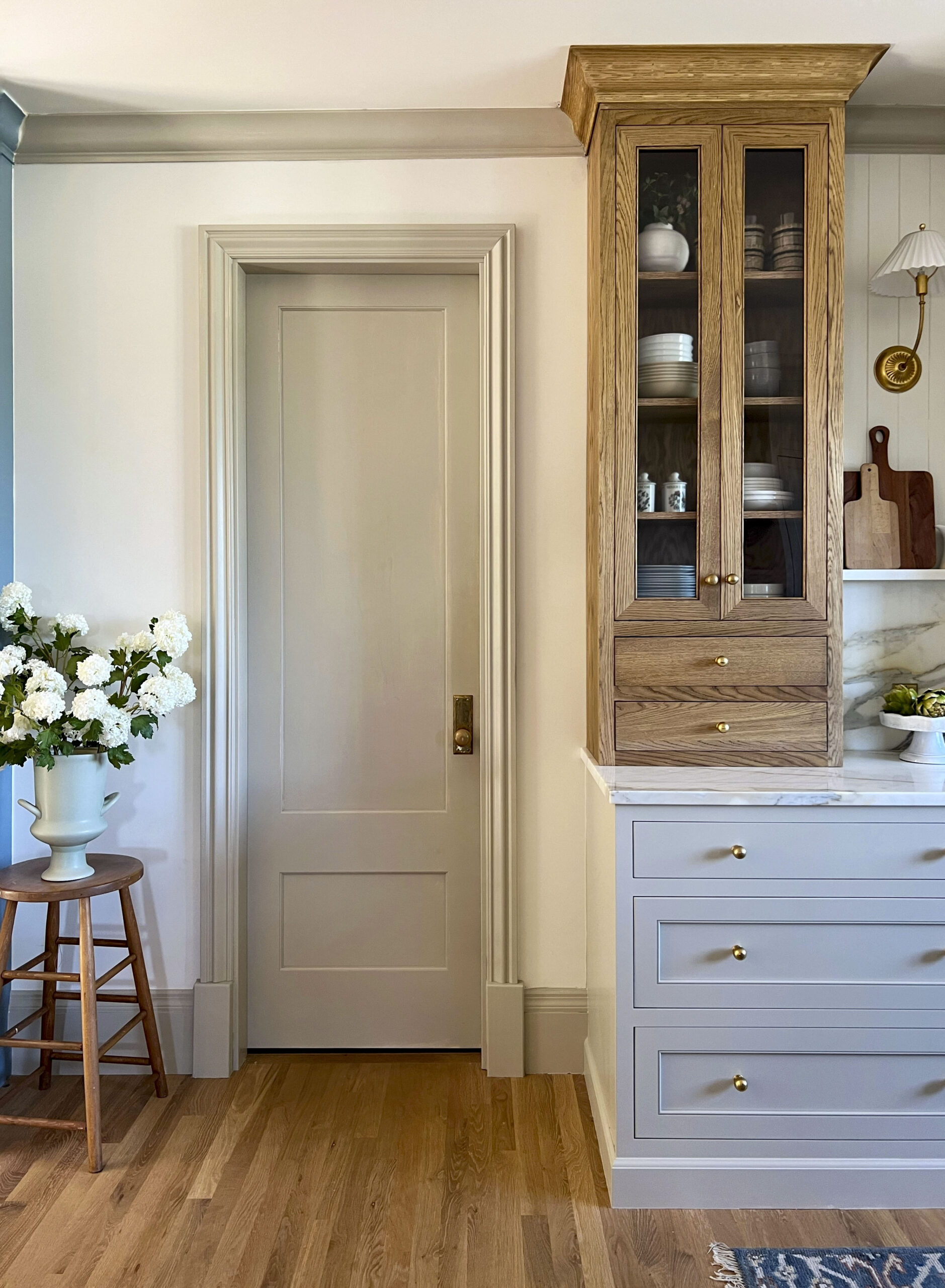 Pale grey painted two-panel interior door beside a wood hutch