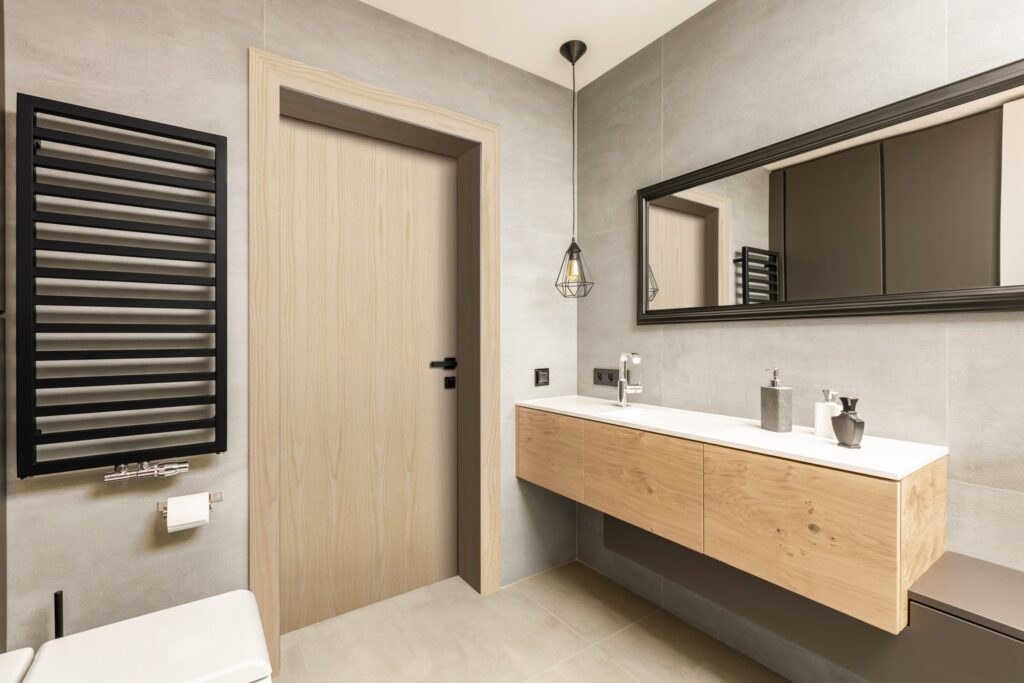 Modern bathroom with a flush light birch door, floating vanity and black towel radiator