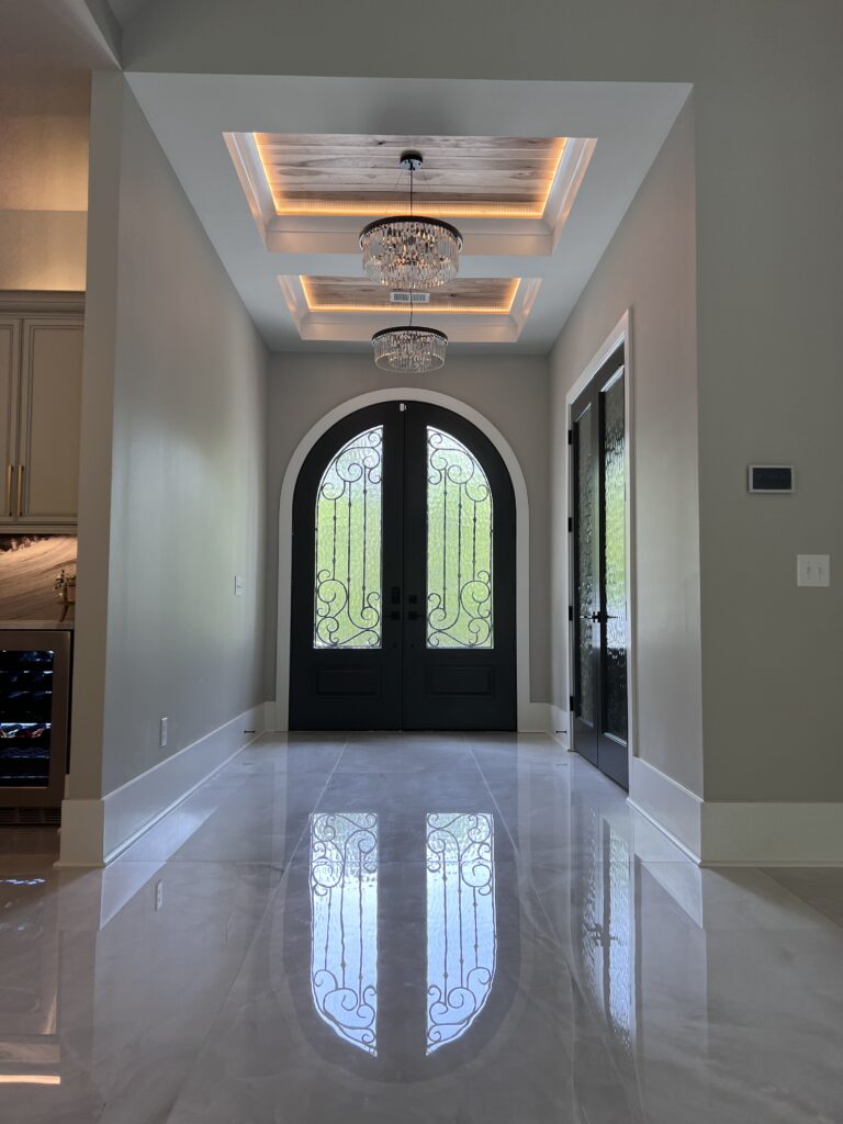 Foyer with arched black double doors with wrought iron glass over polished marble floor