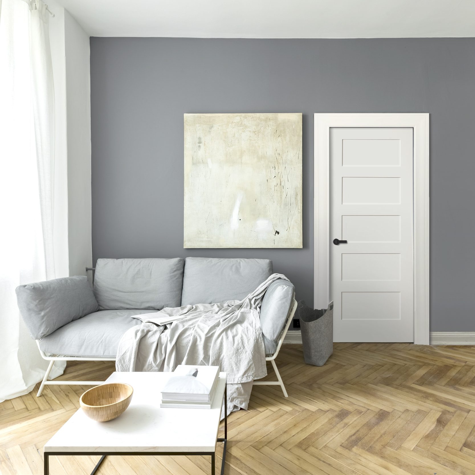 Grey living room with a white three-panel interior door and herringbone floor