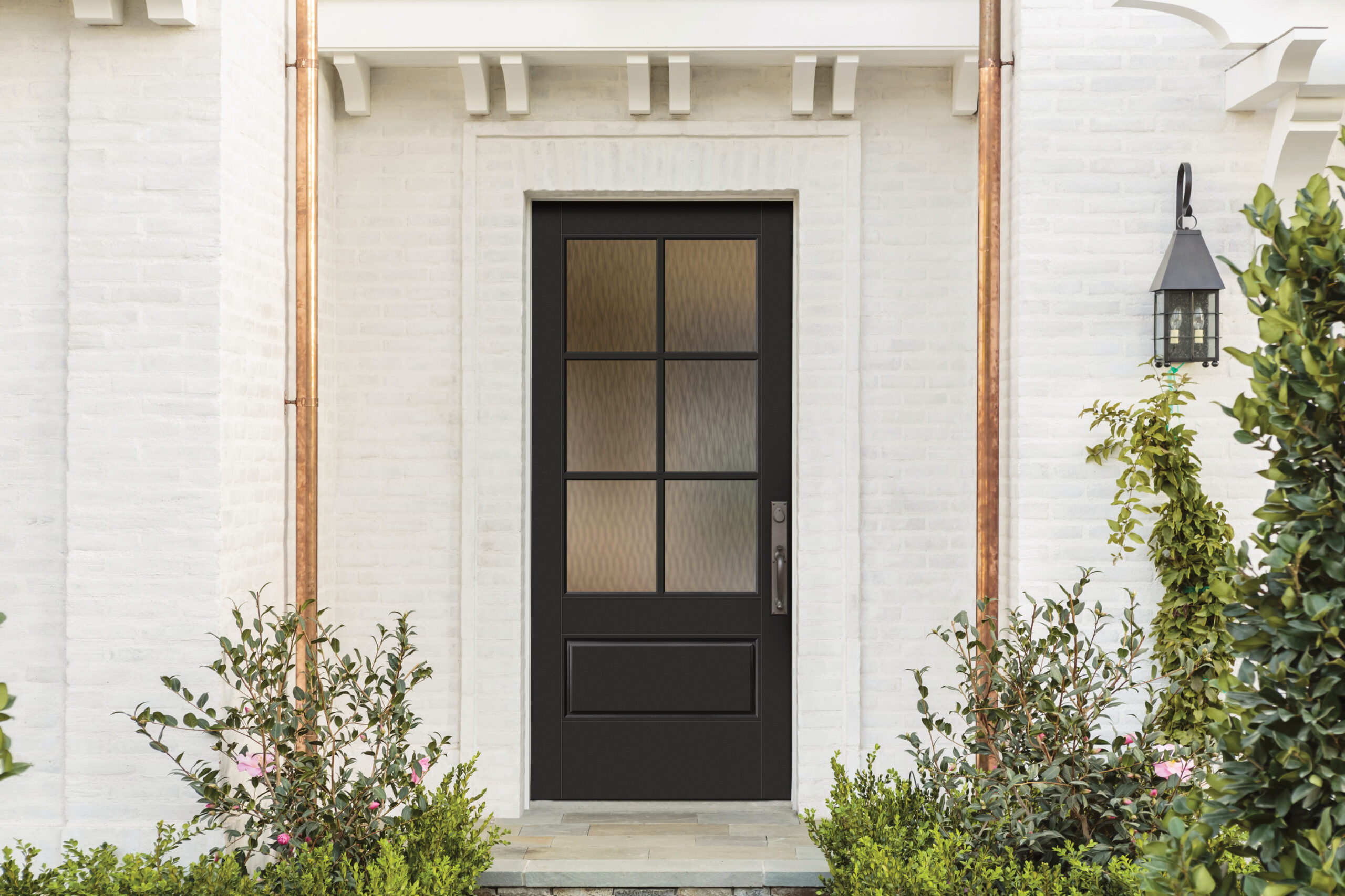 Black craftsman entry door with a six-lite window on white painted brick