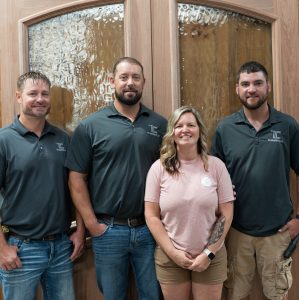 Four TLC Elite team members in front of a wood door with decorative glass