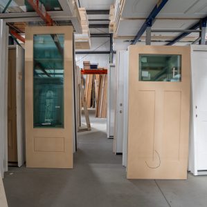 Warehouse racks holding unfinished doors with glass lites